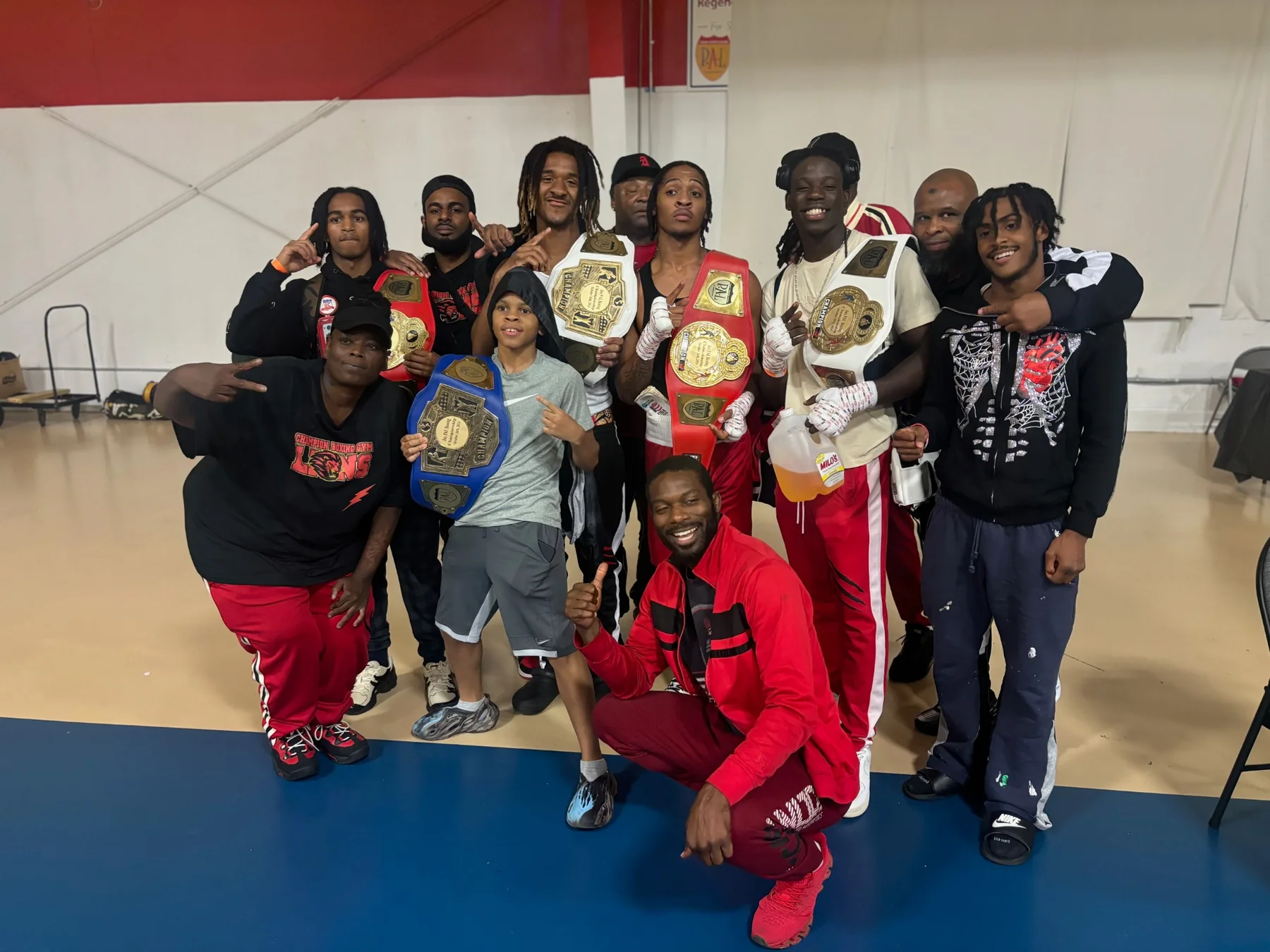 Champion Boxing Gym team posing together with championship belts